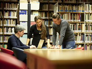 Drei Personen in einer Bibliothek